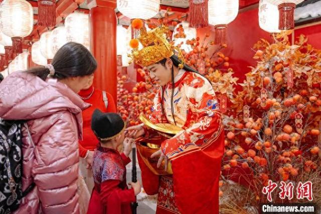图为游客与“财神”在街区内互动。 滕瀚 摄