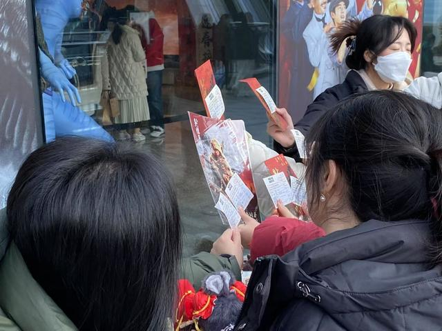 MOVIE MOVIE影院外，影迷晒票根与海报合照。