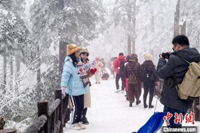 游客在洪雅瓦屋山景区边赏雪景边拍照留念。李霞摄