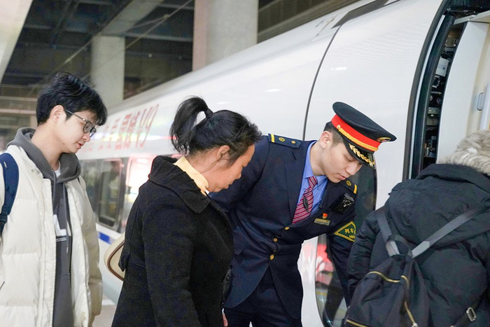 合肥客运段列车长在车门口扶携旅客上车。李正源 图