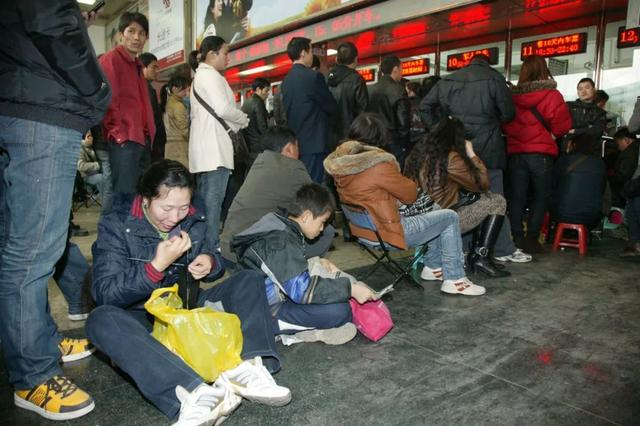 2011年，旅客在南宁火车站售票处自备小板凳排队购票。通讯员 陈孚平 摄
