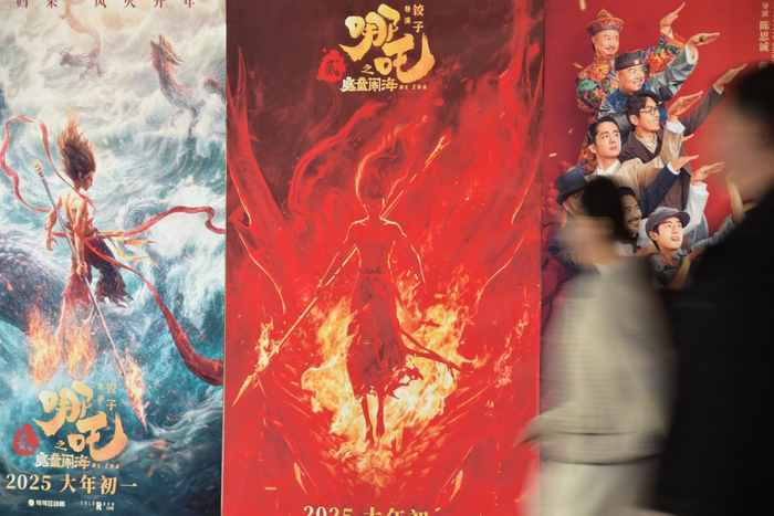 2月2日，观众从云南蒙自市一电影院的春节档电影宣传海报前经过 视觉中国 图