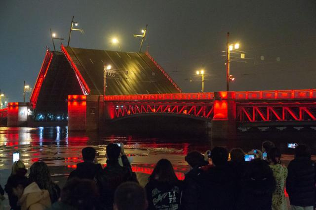 2025年1月29日凌晨，在俄罗斯圣彼得堡，人们在涅瓦河畔观看亮起“中国红”的冬宫桥开桥。新华社发（莫京娜 摄）