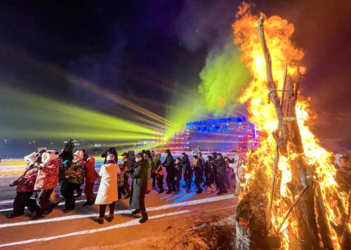 　　在冰雪大庙会，游客围着篝火欢快起舞。资料图片