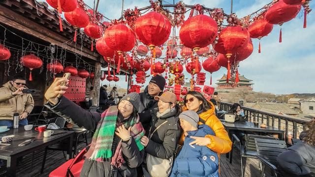 在什刹海岸边的糖房咖啡馆，游客在露台打卡喜庆的节日装饰，观赏中轴线风景。 武亦彬摄