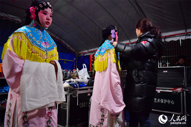 临时搭建的剧团后台里，剧团演员正为年轻一代的演员穿戴演出服饰。人民网记者 时雨摄