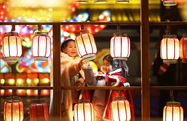 2025年1月31日晚，在山东省临沂市郯城县郯国古城景区，两名穿着传统服饰的小女孩在观赏花灯。 新华社发（张春雷 摄）