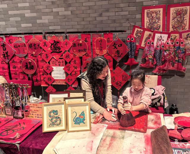 “过年——春节主题展”现场，观众正在体验杨家埠木板年画。（受访者供图）