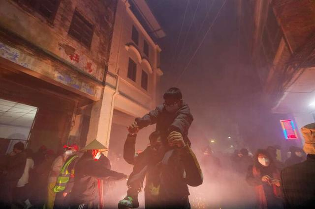 2月8日，广西南宁市宾阳县，一对父子正在经过鞭炮炸响的街道。江畅/摄