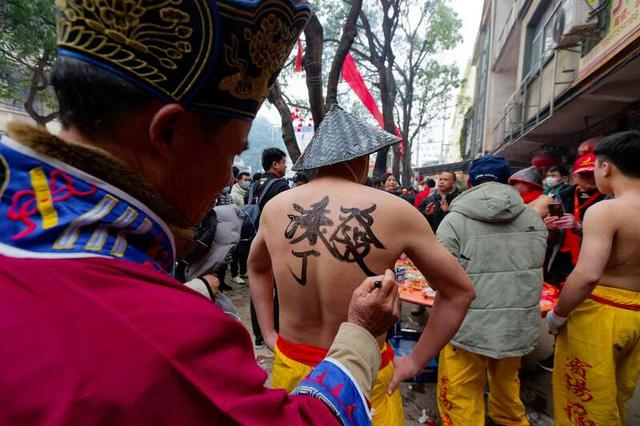 2月8日，广西南宁市宾阳县，当地长辈正在给舞龙勇士写字赐福。江畅/摄