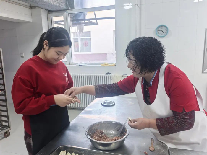 小嘉忆向妈妈的同事学习包饺子。