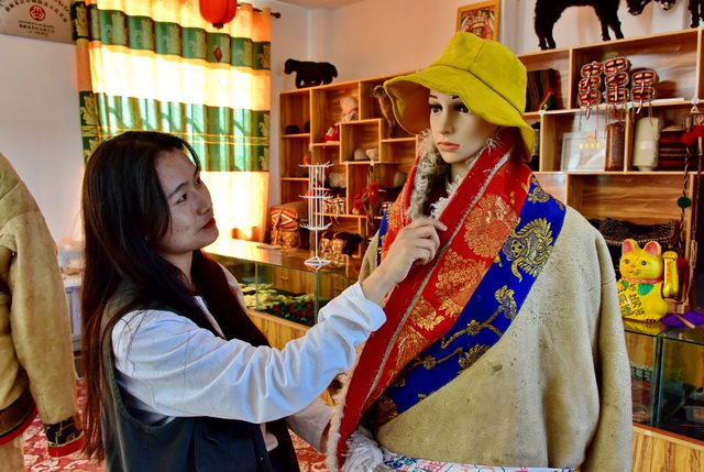 曲麻莱县玛玉泽喇九桑商贸有限公司土畜产品展示厅，一位工人正在整理藏族服饰。摄影/章轲