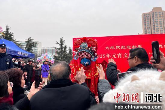 变脸表演吸引群众围观。 马芊芊 摄