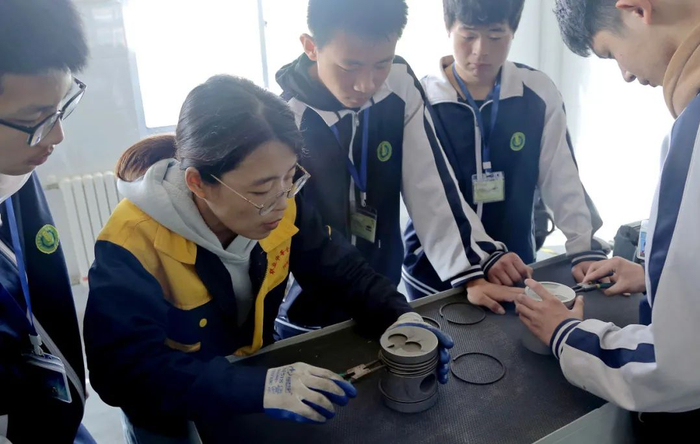 山东青岛平度市职教中心农学专业学生正在教师指导下进行195农用拖拉机单缸发动机活塞环装配练习。（中国教育报记者 孙军 摄）