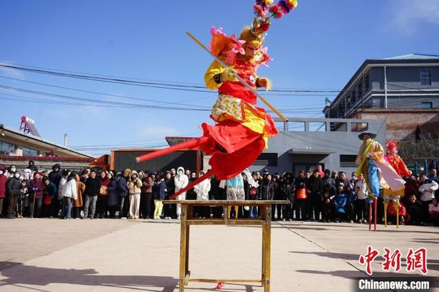 图为2月12日，在河北省滦平县长山峪镇长山峪村，当地民间艺人踩高跷跳跃桌子。 梁志青 摄