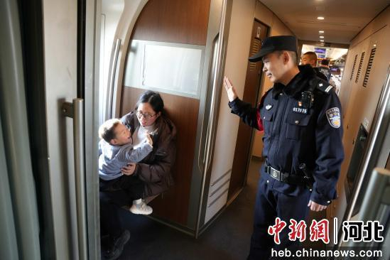 图为石家庄铁路公安处乘警支队乘警杜雪在路过车厢连接处时，一名小朋友非常热情的主动向杜雪打招呼。 贾义涵 摄
