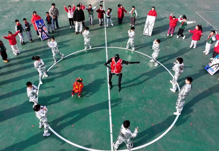 △ 2025年2月13日，武汉市未来实验美林小学学生与智能机器狗和人形机器人共舞（无人机照片）。新华社发（赵军摄）