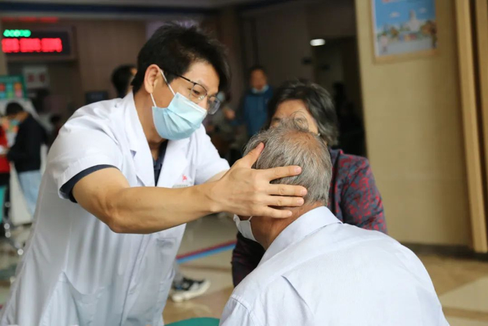 △陆辉主任在义诊时，为慢性疼痛患者做检查