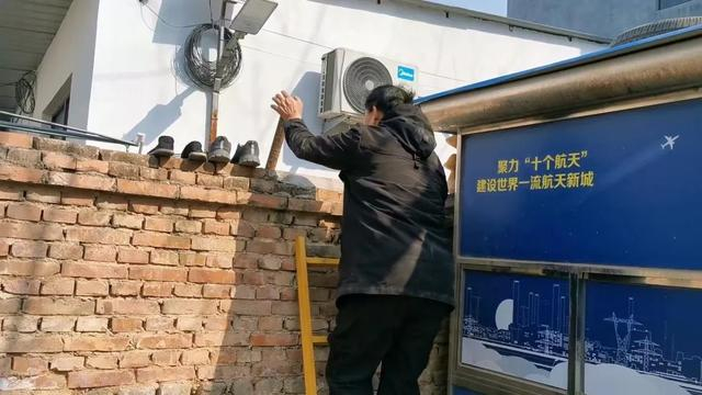 因门外围观的人太多，朱之文与邻居在共用的墙上架起梯子通行。图/九派新闻 温艳丽