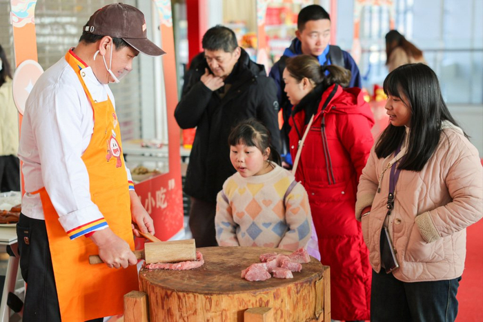 2025年1月10日，三明北站非遗文化进车站活动中，小旅客在观看沙县小吃制作技艺。 黄育仁 摄