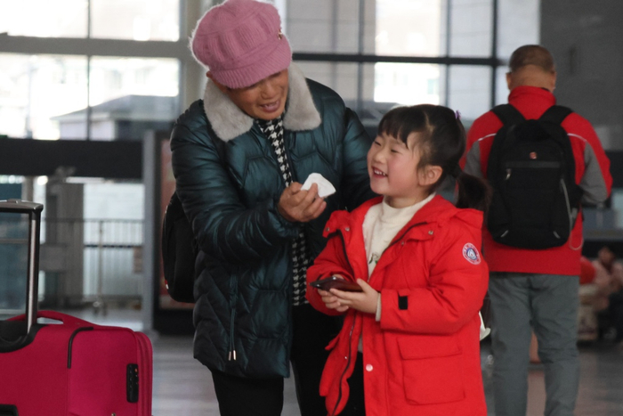 “反向春运”旅途中，祖孙俩在车站与亲人视频，脸上洋溢着幸福的笑容。谢珺 摄