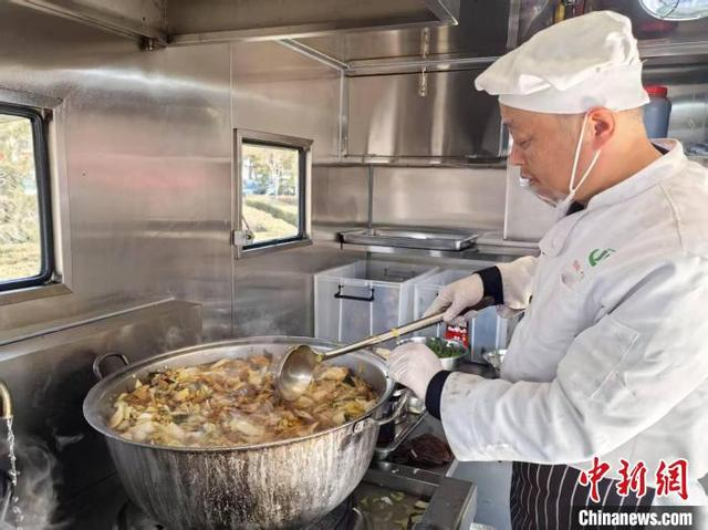工作人员在餐车上用小锅加做烩菜，确保足量供餐。 陆祁国 摄