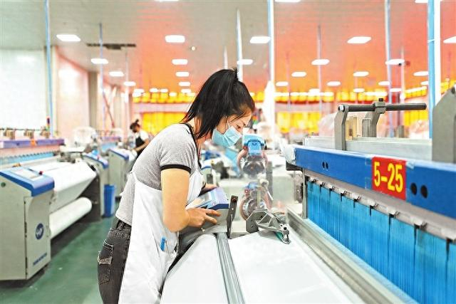 邓州市吴江化纤工人在查看织机运转情况。 王崇顺 摄