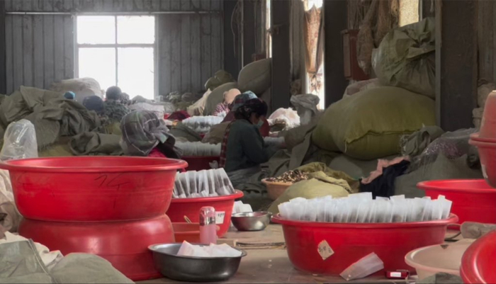 村里留守老人在车间将原材料装进无纺布袋，车间内粉尘严重，工人们自备口罩 来源：澎湃新闻