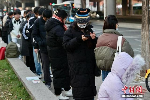 资料图：2025年国考考点外，考生抓紧时间复习。中新社记者 易海菲 摄