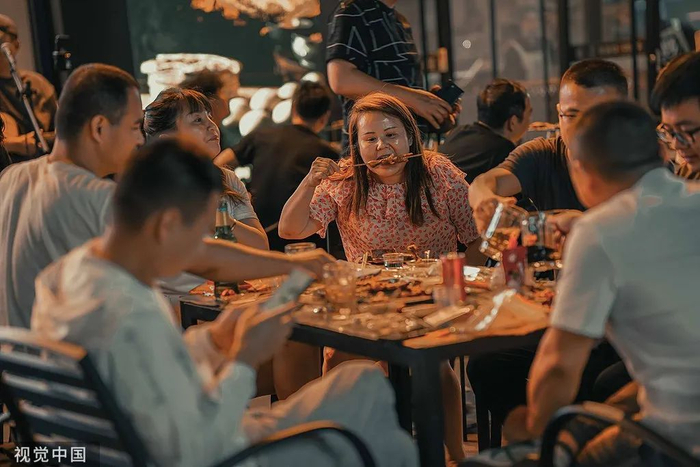 人们在夜市上的烧烤摊聚会。视觉中国供图