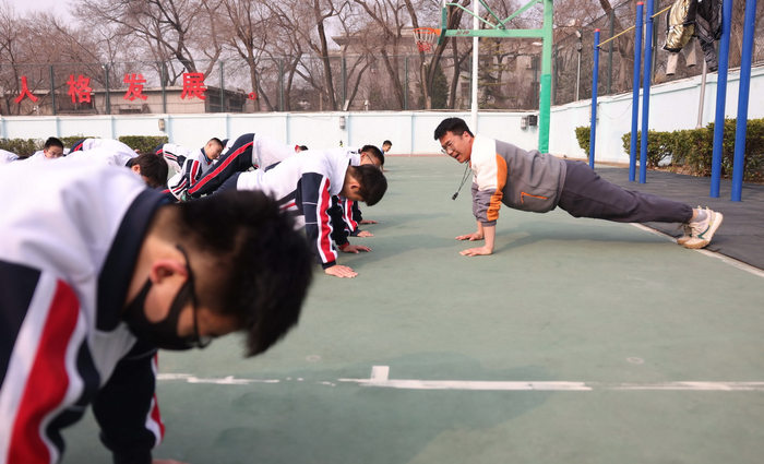 3月10日上午，东直门中学操场，体育教师崔佳峰和男生一起做俯卧撑。新京报记者 李木易 摄