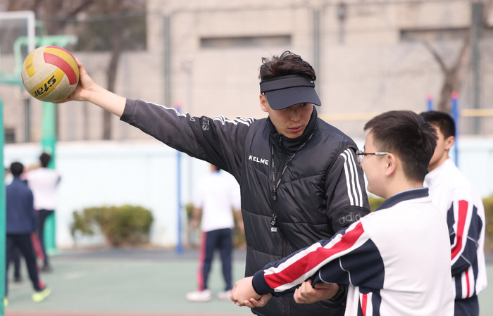 3月10日上午，东直门中学操场，排球课上，体育教师霍帅在辅导学生垫球练习。新京报记者 李木易 摄