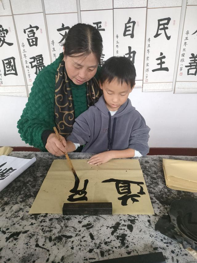 在柯城区沟溪乡五十都书画社里，毛美仙正在教村民写书法。受访者供图
