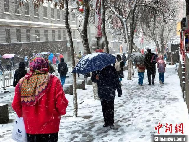 图为民众冒雪出行。中新社记者 王小军 摄