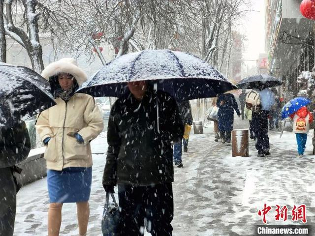 图为民众冒雪出行。中新社记者 王小军 摄