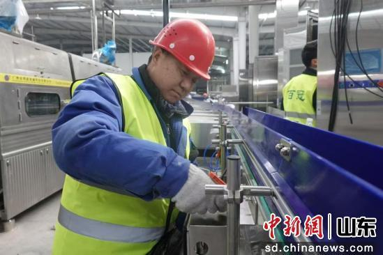 在鲁西新区优典大健康饮品项目施工现场，身着统一工装的技术工人正紧张有序地进行设备的安装调试作业。孙安琪 摄