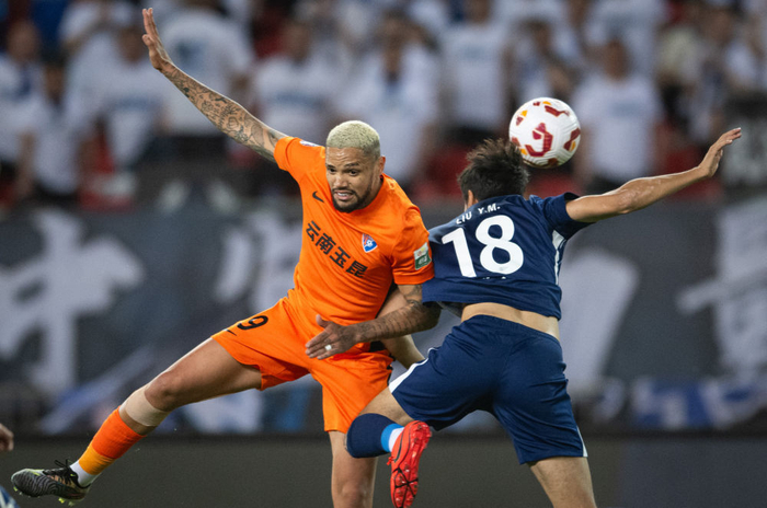 4月12日，云南玉昆队球员恩里克（左）与武汉三镇队球员刘奕鸣争顶。 新华社记者 肖艺九 摄