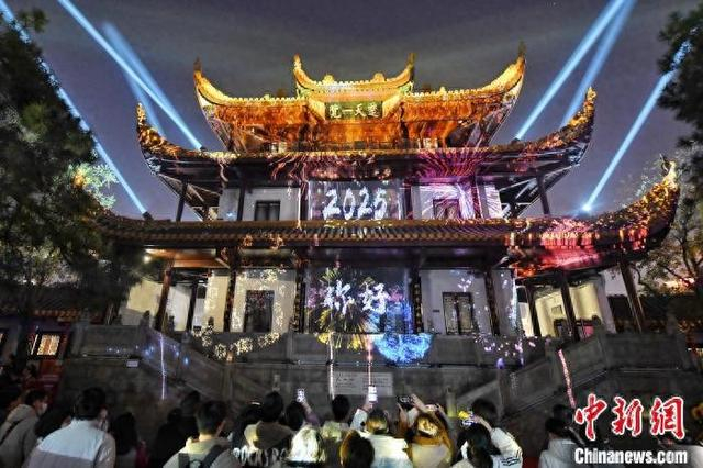2025年1月1日，湖南长沙天心阁与国金中心同时点亮灯光。图为游客在天心阁观看新年灯光秀。 中新网记者 杨华峰 摄