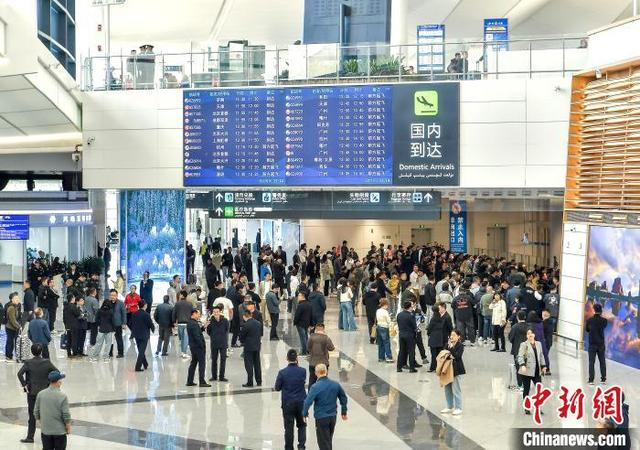 4月17日，乌鲁木齐天山国际机场北区航站楼正式转场试运行，民众聚集在国内到达通道口等待接机。中新社记者 刘新 摄