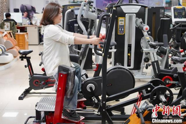4月17日，在义乌国际商贸城一家主营体育用品的店铺，商户贾英玲示范如何使用“深蹲机”。董易鑫 摄
