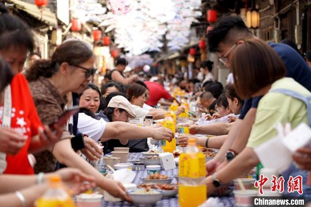 图为长街宴正式开餐，大家有的举杯，有的夹菜，有的打卡拍照，现场热闹非凡。中新社记者 吕杨 摄