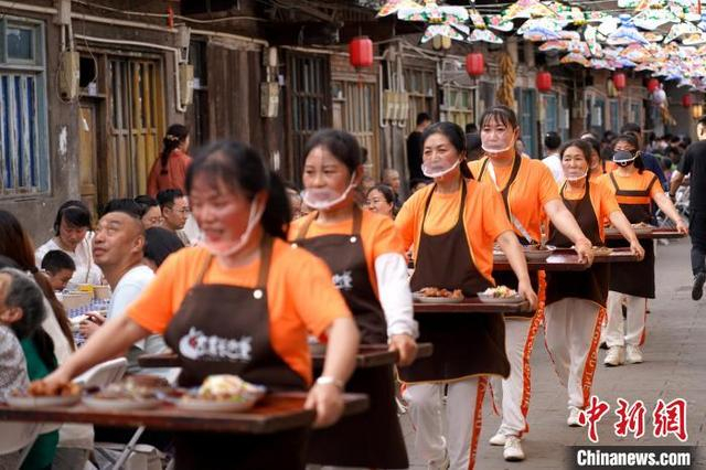 图为工作人员排成一列传菜上桌。中新社记者 吕杨 摄