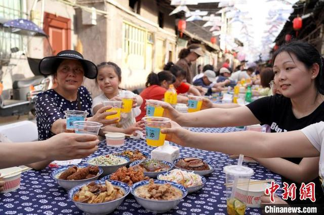 图为游客和当地居民欢聚一堂，共同举杯。中新社记者 吕杨 摄