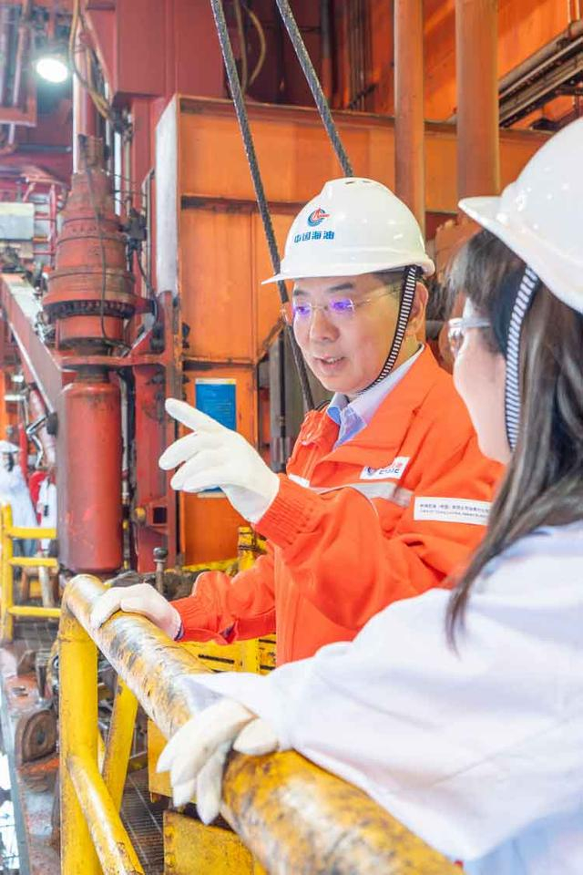 图注：中国海油研究总院总工程师、钻完井专家李中与工作人员在作业现场进行交流沟通