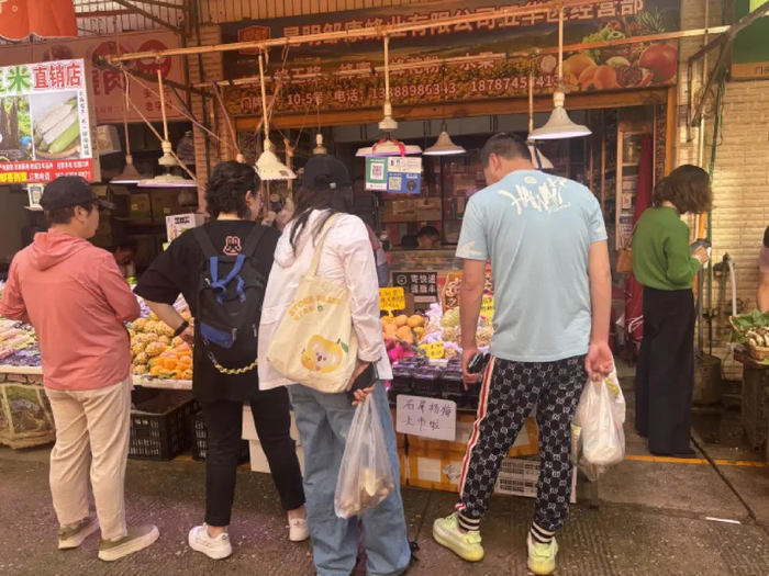 在水果摊前驻足品尝询价杨梅的市民