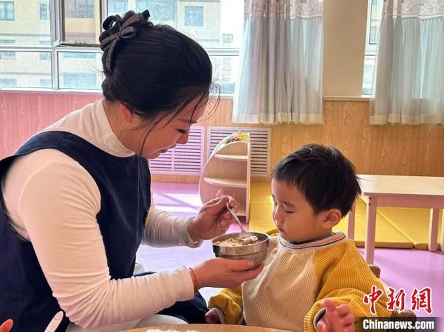 图为老师给孩子喂饭。 戴文昌 摄