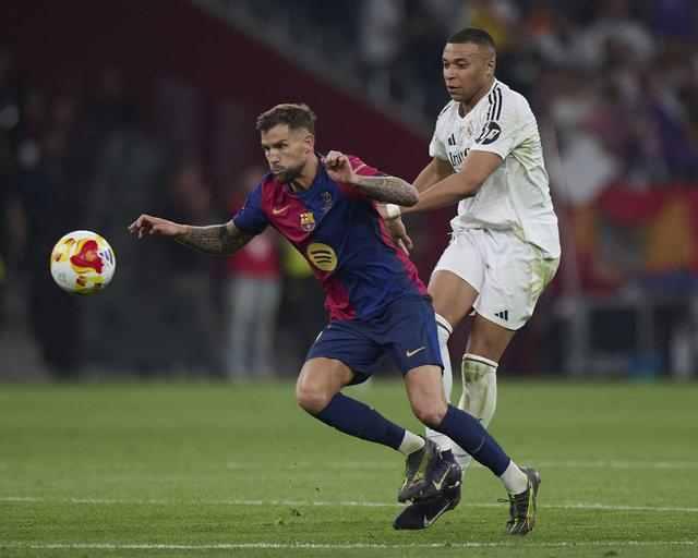 4月26日，巴塞罗那队球员伊尼戈·马丁内斯（左）和皇家马德里队球员姆巴佩在比赛中拼抢。新华社发（帕布罗·莫拉诺 摄）