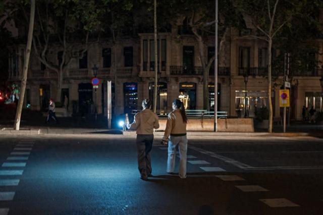 4月28日，在西班牙巴塞罗那，一名女子用手机的手电筒照明穿过人行道。新华社 图