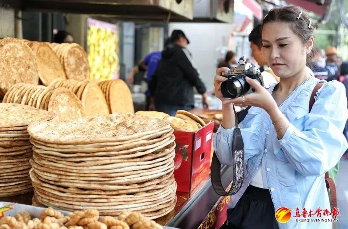 4月27日，在和田二街，一名来自四川的游客拍摄特色美食。资料图片