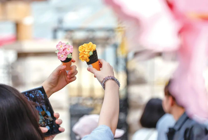 2025年4月4日，在天津市五大道风景区，游客手举海棠花造型雪糕拍照留影